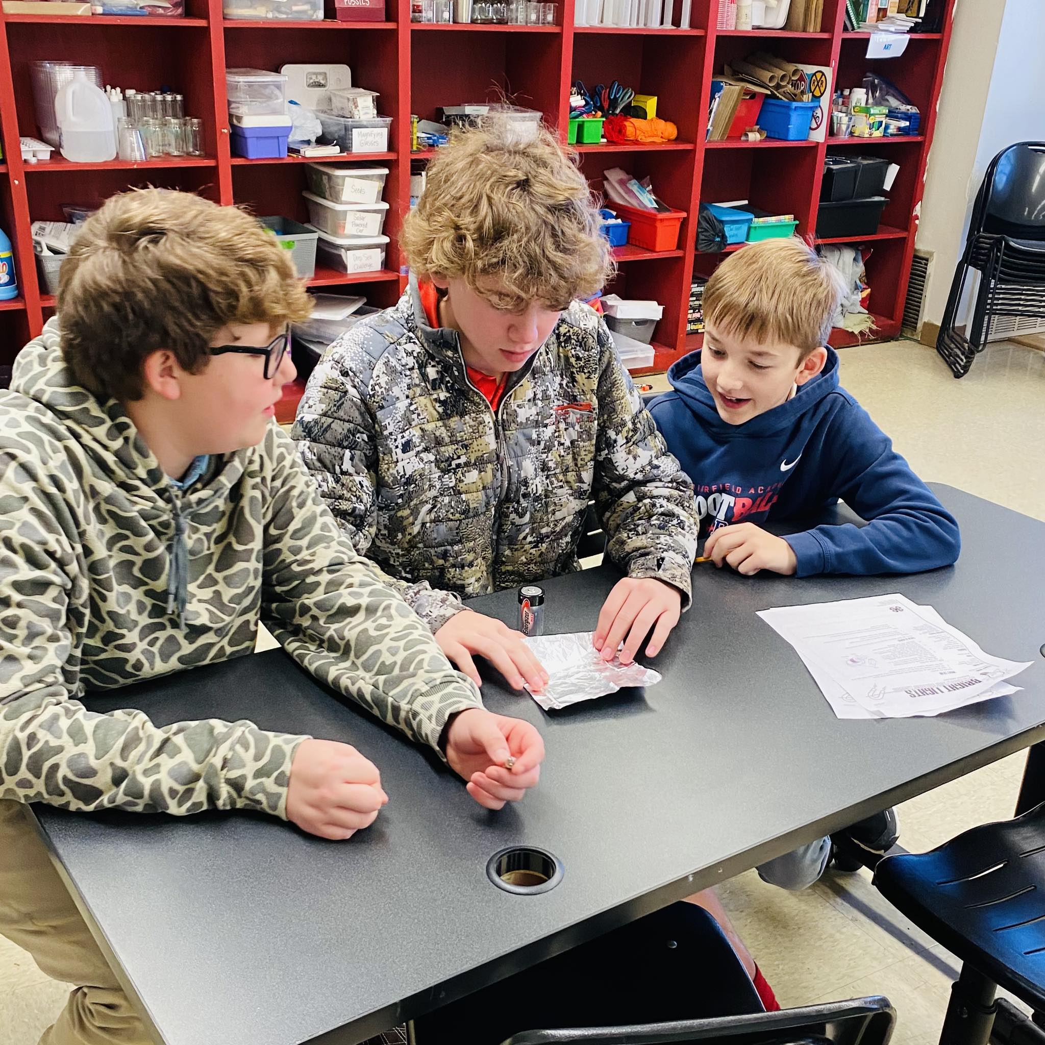 Three boys reading a paper.